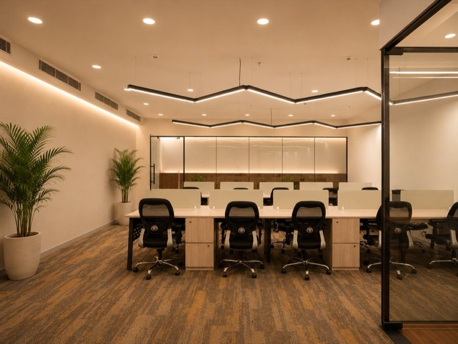 QAARYA workspace with rows of desks, warm lighting and indoor plants